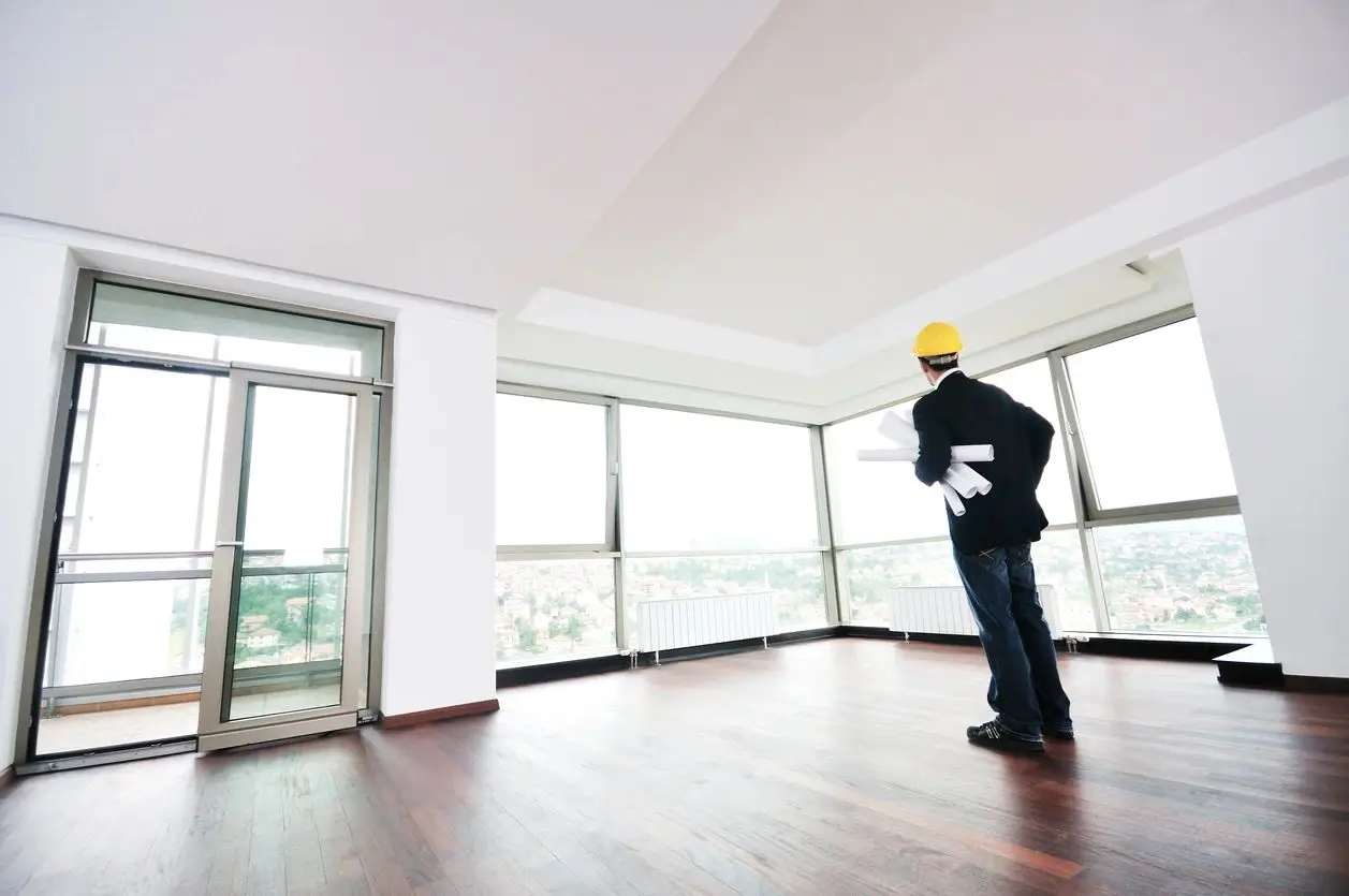 A man standing in an empty room with windows.