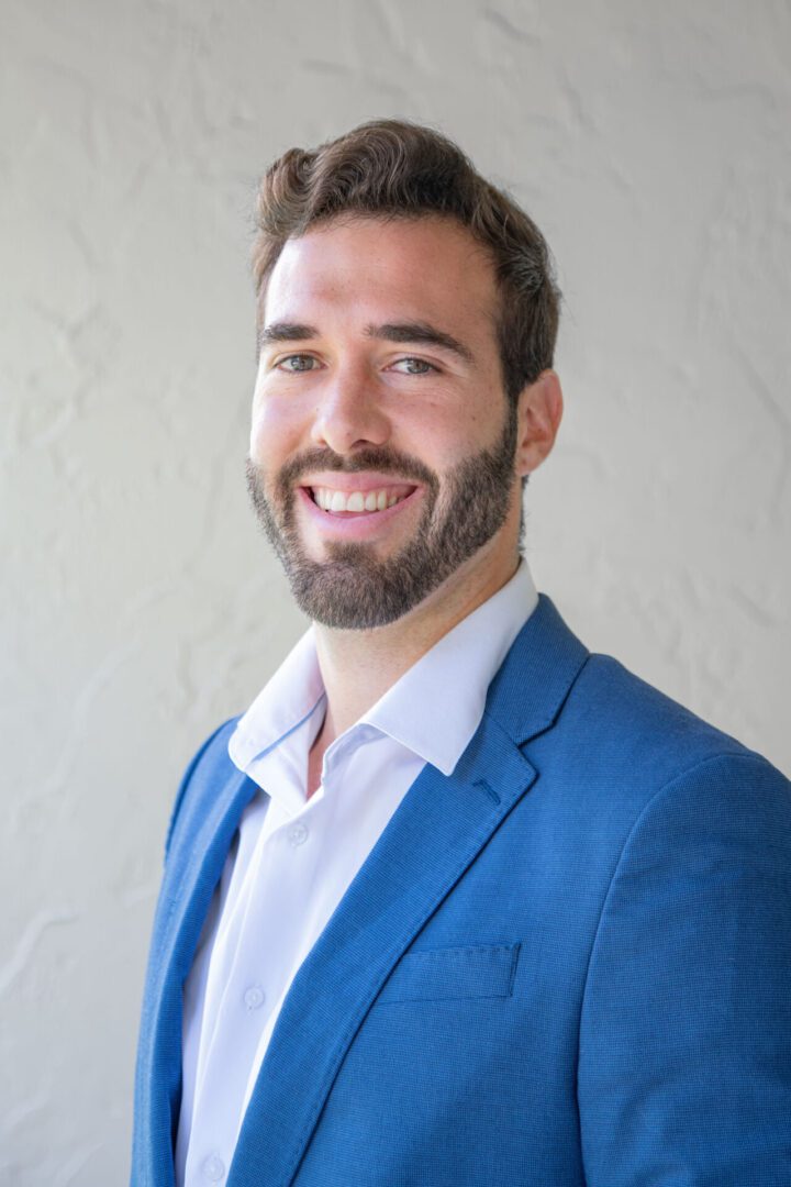 A man in a blue suit smiling for the camera.