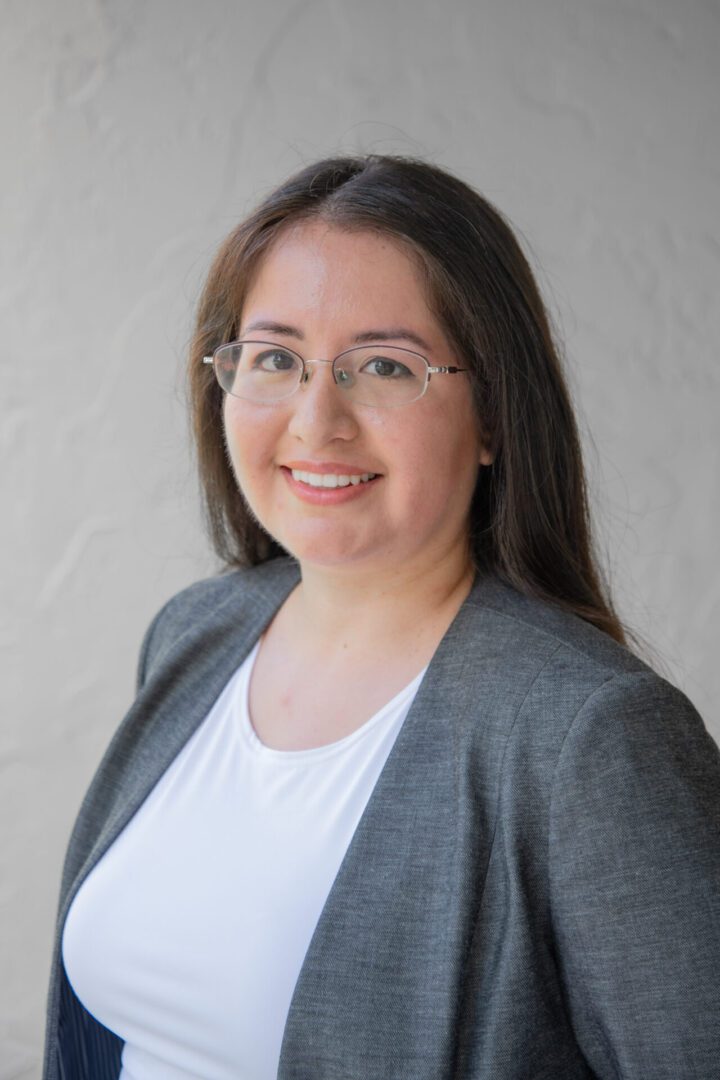 A woman with glasses and a gray jacket