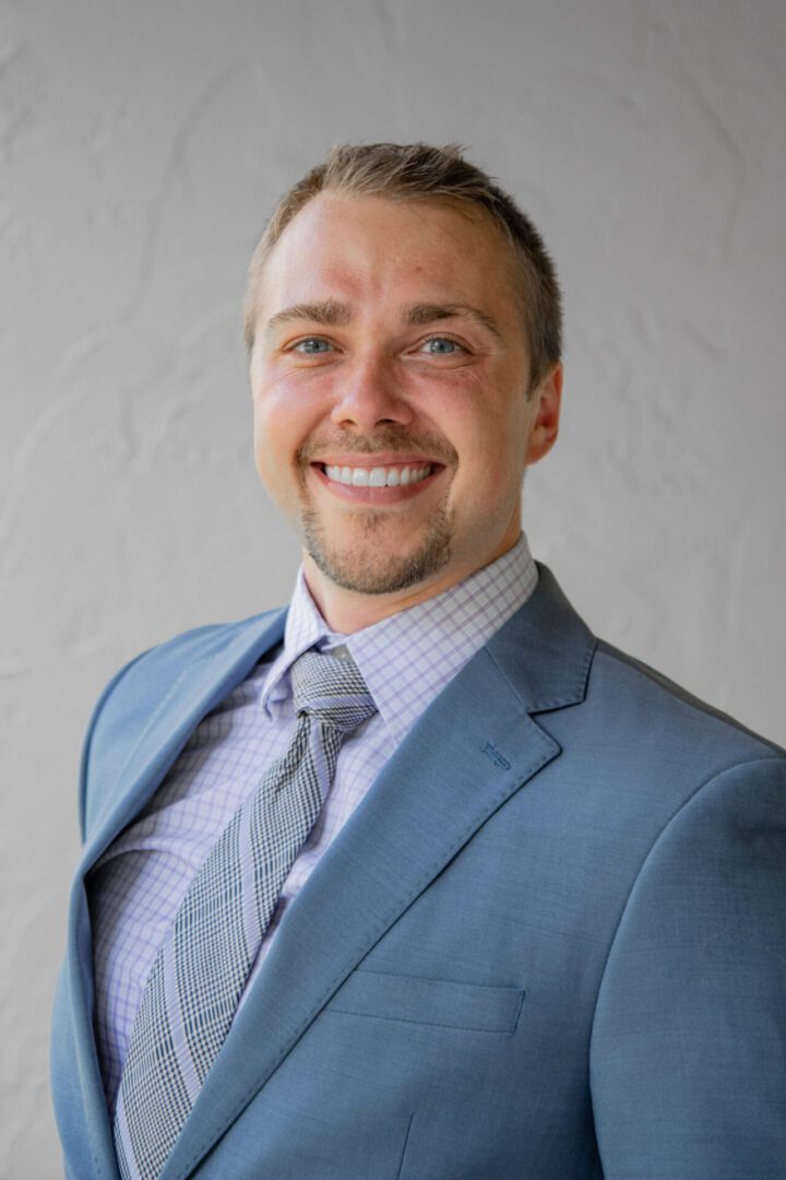 A man in a suit and tie smiling for the camera.