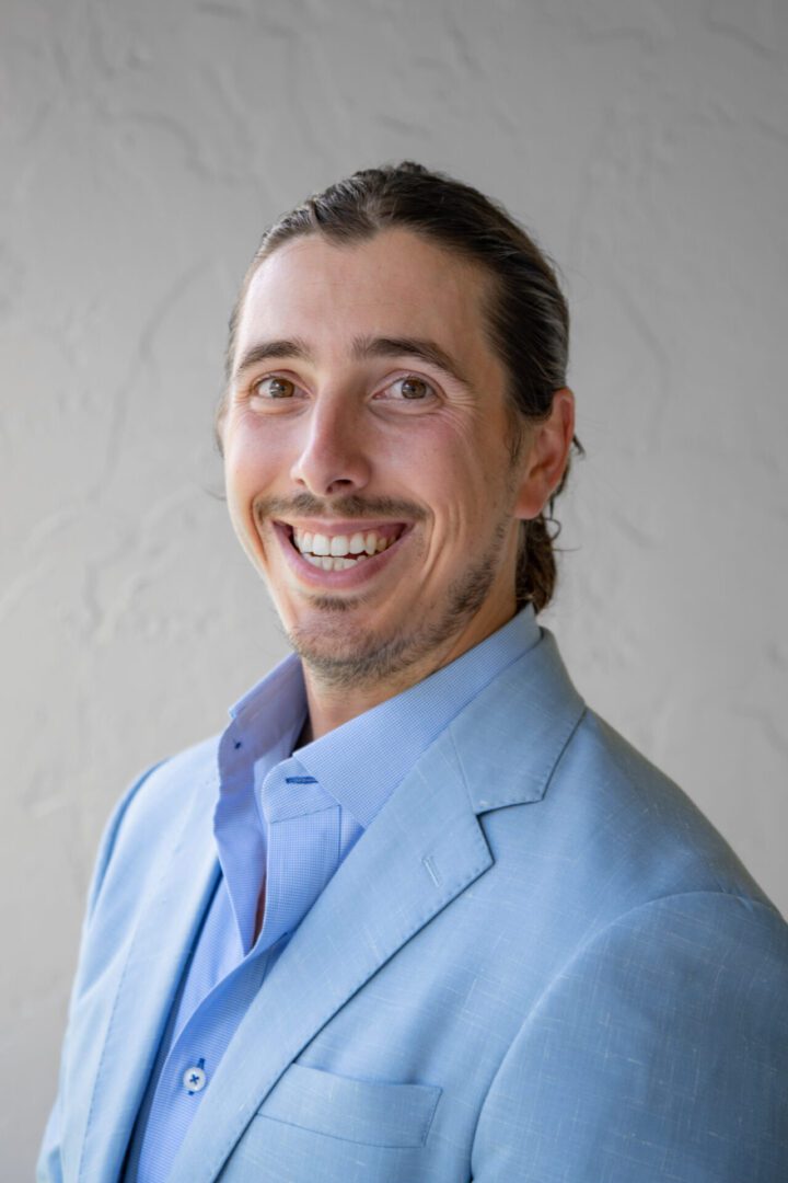 A man in a blue suit smiling for the camera.