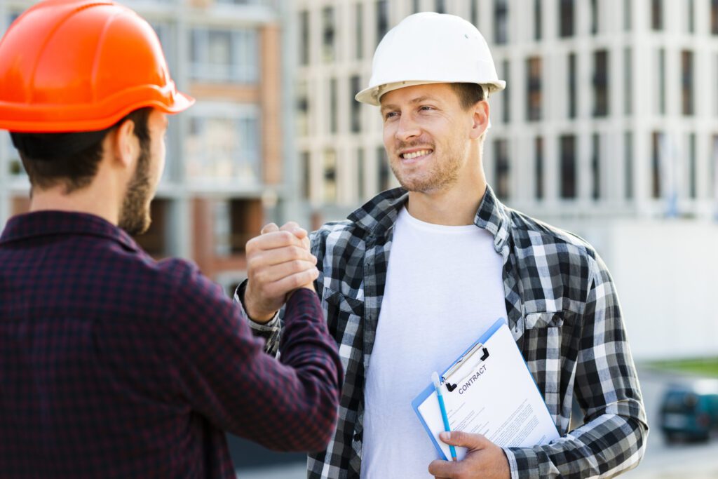 Two men shaking hands while wearing hard hats.