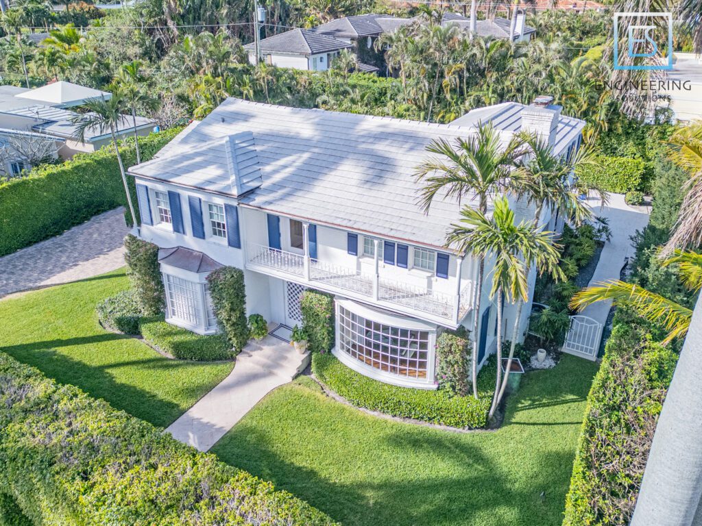 A large white house with palm trees in the yard.